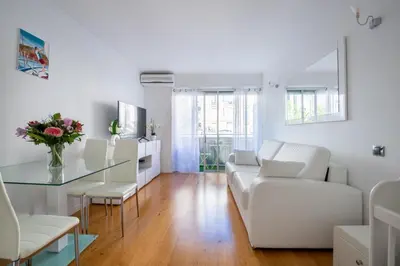 a white living room with a glass table and white chairs at Azur Central Flat in Nice