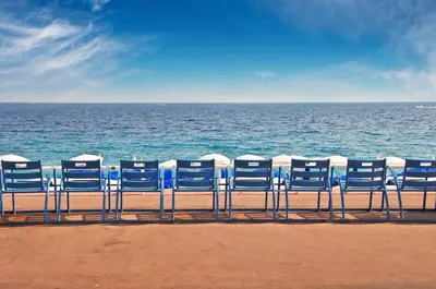 a row of blue chairs sitting on the beach at Azur Central Flat in Nice