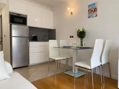 a kitchen with a table with white chairs and a refrigerator at Azur Central Flat in Nice