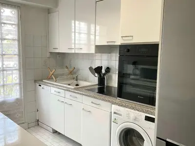 a kitchen with white cabinets and a washer and dryer at Lympia - one bedroom apartment near the port in Nice