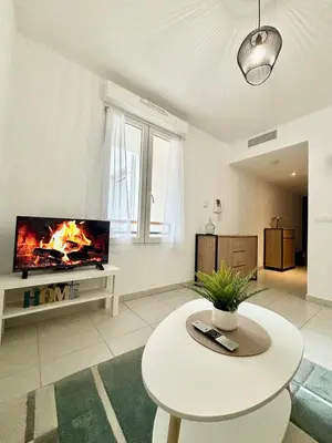 a living room with a tv and a table at Nid douillet rénové et tramway à 1 min in Nice