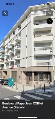a large white apartment building with a car parked in front at Nid douillet rénové et tramway à 1 min in Nice