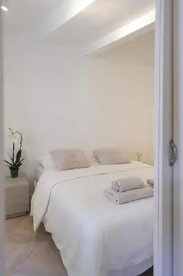a white bedroom with a bed with white sheets and pillows at Magnifique appartement proche mer in Nice