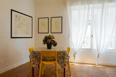 a dining room table with yellow chairs and a vase of flowers at Riviera Prom 4 Pers Vista Mare in Nice