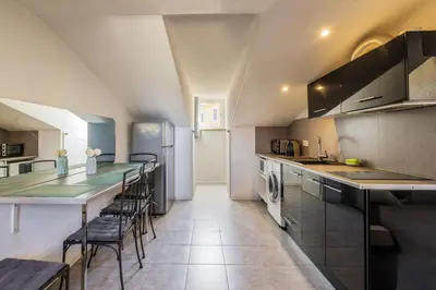 a kitchen with a long counter and chairs in it at Perchoir dans la vieille ville in Nice