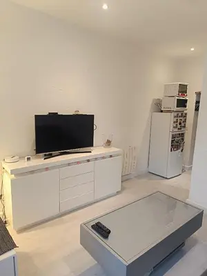 a white living room with a tv and a white refrigerator at Appart in Nice