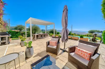 a patio with a table and chairs and an umbrella at Villa de prestige Vue mer panoramique Piscine Climatisation in Nice