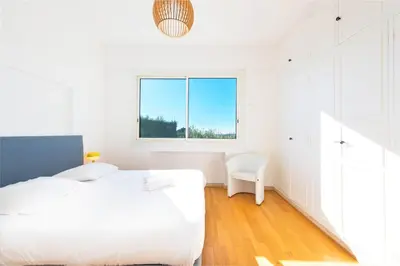 a white bedroom with a bed and a window at Villa Grenouillere - Vue Mer - Fitness - Sauna in Cagnes-sur-Mer