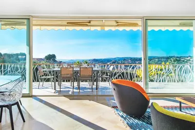 a living room with a table and chairs on a balcony at Villa Grenouillere - Vue Mer - Fitness - Sauna in Cagnes-sur-Mer