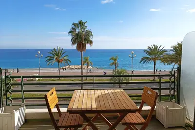 a wooden table and chairs with a view of the beach at Charming T1 with terrace and sea view in Nice