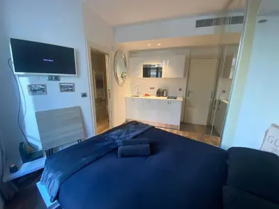 a bedroom with a blue bed and a kitchen at Cosy Studio Promenade in Nice