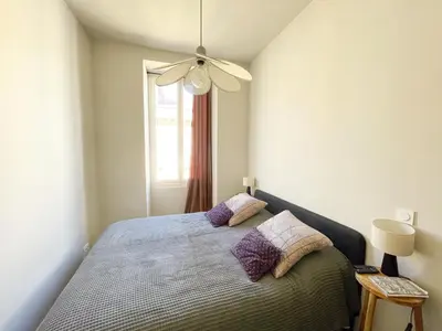a bedroom with a bed with purple pillows and a window at Appartement cozy au coeur de Nice in Nice