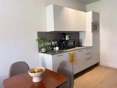 a kitchen with white cabinets and a wooden table at Appartement cozy au coeur de Nice in Nice