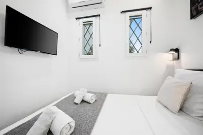 a white bedroom with a bed with a flat screen tv at Bleu Rivage - Magnifique 2P au Port de Nice - 1 chambre et 1 Mezzanine in Nice