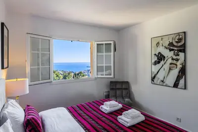a bedroom with a bed and a chair and a window at Elegance, serenite et vue exeptionnelle sur la rade in Villefranche-sur-Mer