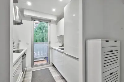 a white kitchen with a refrigerator and a window at Flat with balcony 15min from Promenade des Anglais in Nice