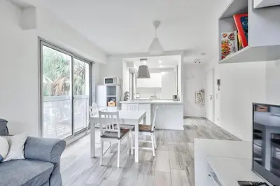 a white kitchen and living room with a table and chairs at Flat with balcony 15min from Promenade des Anglais in Nice