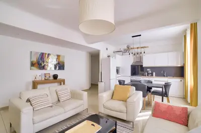 a living room with white furniture and a kitchen at Stunning 2BR by the Port 20min Walk to the Beach in Nice