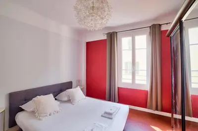 a bedroom with a bed with red walls and a chandelier at Stunning 2BR by the Port 20min Walk to the Beach in Nice