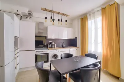 a kitchen with a table and chairs in a kitchen at Stunning 2BR by the Port 20min Walk to the Beach in Nice