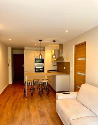 a living room with a couch and a kitchen at Superbe appartement 2 pièces avec piscine in Nice