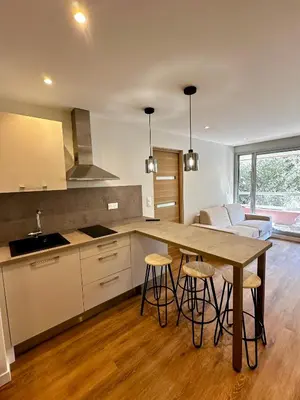 a kitchen with a table and stools in a room at Superbe appartement 2 pièces avec piscine in Nice