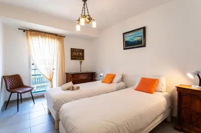 a bedroom with two beds and a chair and a window at Jardin Wilson AP4455 by RIVIERA HOLIDAY HOMES in Nice