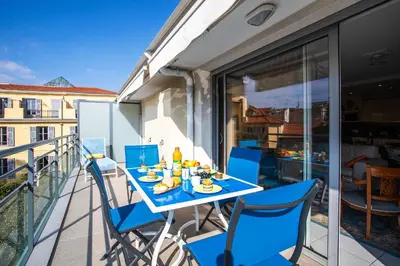 a table on a balcony with blue chairs at Jardin Wilson AP4455 by RIVIERA HOLIDAY HOMES in Nice