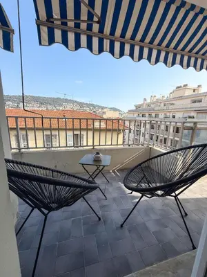 a balcony with two chairs and a table and an umbrella at appartement port de Nice 4pers emplacement idéal in Nice