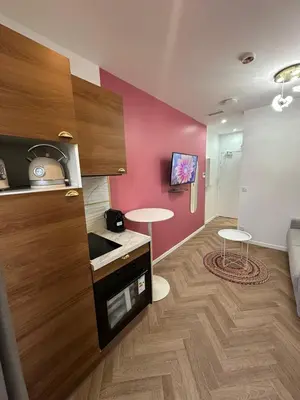 a kitchen with a pink wall with a table and two stools at MOON - 33 in Nice