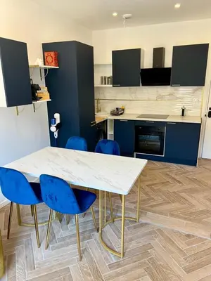 a kitchen with a white table and blue chairs at MOON - 34 in Nice