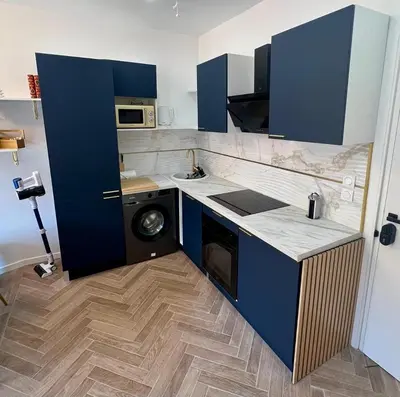a kitchen with blue cabinets and a washing machine at MOON - 34 in Nice