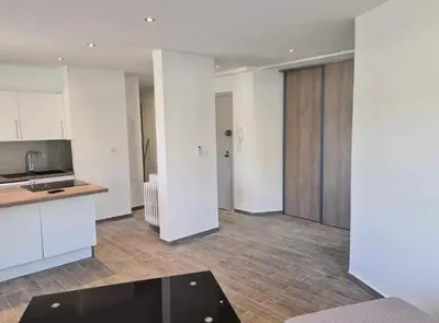a kitchen with white cabinets and a black table at Vacances à Nice in Nice