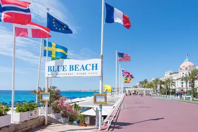 a boardwalk with flags of different countries on the beach at FLEUR- Cosy Studio, 200 Promenade des Anglais et Negresco, wifi, climatisation- calme in Nice