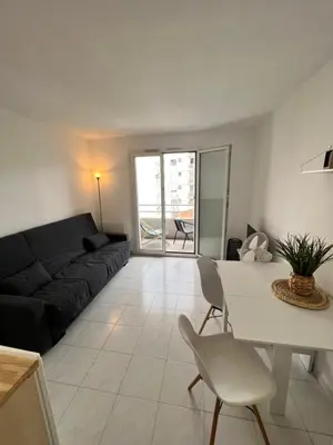 a living room with a black couch and a table and chairs at Nice center - 2 person apartment in Nice