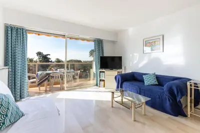a living room with a blue couch and a balcony at Happyfew appartement les palmiers in Nice