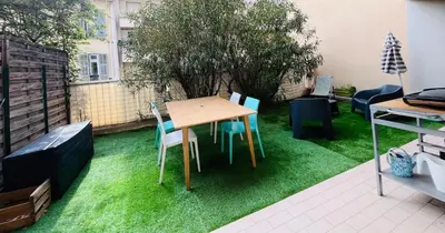 a patio with a table and chairs on grass at Appartement avec grande terrasse in Nice