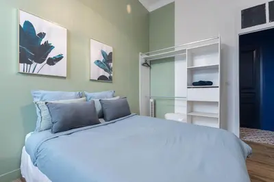 a bedroom with a large white bed with blue pillows at Noa house in Nice