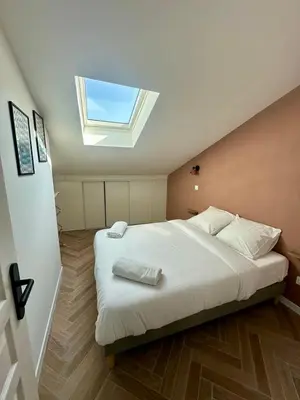a bedroom with a large white bed with a skylight at GIOFFREDO SUITE in Nice
