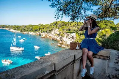 a woman sitting on a wall taking a picture of the water at Nice modern flat in Nice