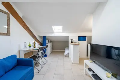 a living room with a blue couch and a kitchen at Cosy studio proche Gare de Nice in Nice