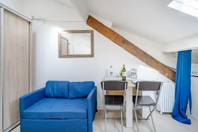a living room with a blue couch and a table at Cosy studio proche Gare de Nice in Nice