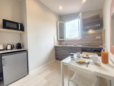 a small kitchen with a white table and a window at Nestor&Jeeves - VIEUX NICE SUITE - Studio - Centre in Nice