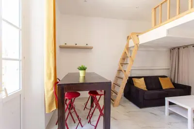a living room with a table and a staircase at GIOA- Studio avec balcon, place Garibaldi -Paillon in Nice