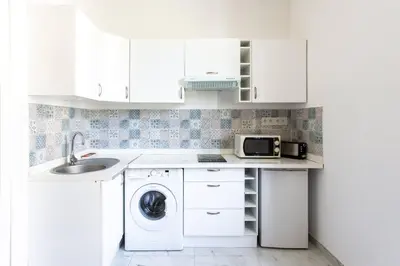 a white kitchen with a washing machine and a sink at GIOA- Studio avec balcon, place Garibaldi -Paillon in Nice