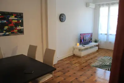 a living room with a dining table and a television at LE REX Nice in Nice