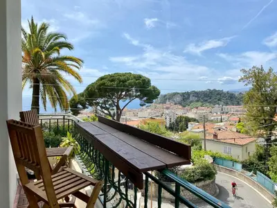 a balcony with a wooden bench and a view of a city at Nice Sea View 2 bedroom apartment in Nice