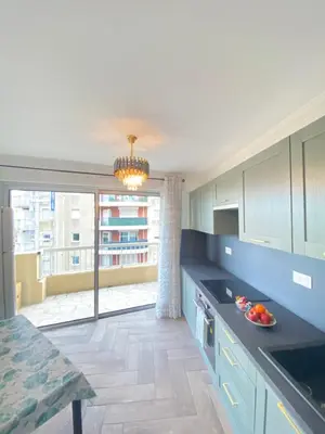 a kitchen with blue cabinets and a large window at Appart T2 refait à neuf 50m2 in Nice
