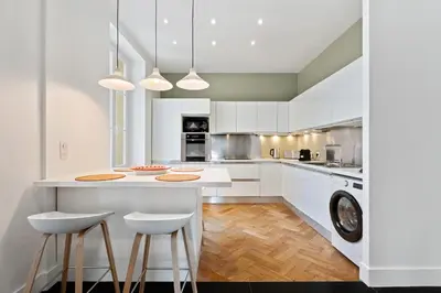 a kitchen with white cabinets and a island with two stools at Nice Renting - VICTOR - Historic Palace Luxury 3 Bedrooms in Nice