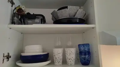 a shelf with bowls and other items in a closet at Carré d'Or - Studio lumineux à 5 minutes de la plage in Nice